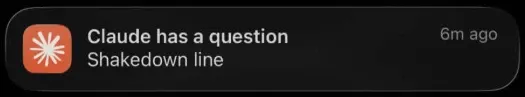 An iOS push notification titled “Claude has a question,” naming the pending question as “Shakedown line”